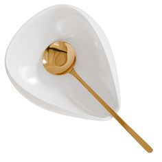 a white bowl with a gold spoon in it and a round shaped object on the side