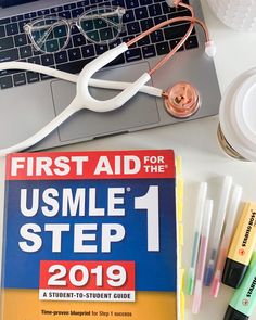 the first aid for the usmle 1 step - by - step guide is next to a laptop