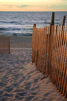 a wooden fence on the beach next to the ocean