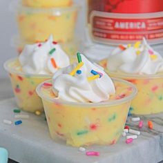 three cupcakes with white frosting and sprinkles on a tray