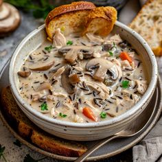 a bowl of mushroom soup with bread on the side