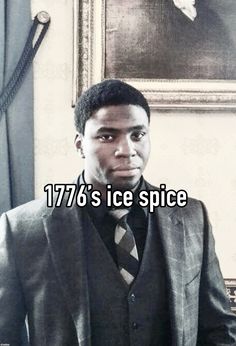 a man wearing a suit and tie standing in front of a painting with the caption 777 is ice spice