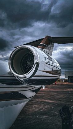 an airplane is parked on the tarmac under a cloudy sky with dark clouds in the background