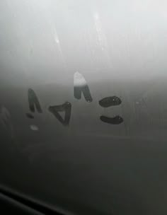 rain drops on the side of a car window with letters written in black and white