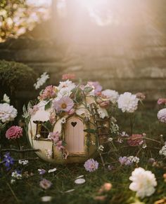 there is a small house made out of flowers in the grass with sunlight coming through