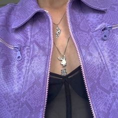 a close up of a person wearing a purple jacket and black top with an animal charm on it's chest