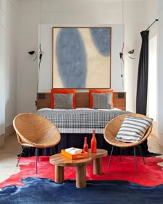 a bedroom with two wicker chairs and a bed in the corner, on top of a red rug