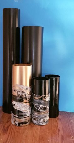 three black and gold vases sitting on top of a wooden table