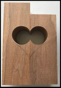 a wooden box with two holes in the middle and a string attached to it that is shaped like a heart