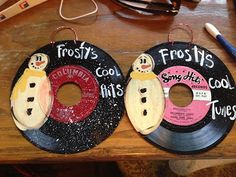 two records with snowmen on them sitting on a table next to a pair of scissors