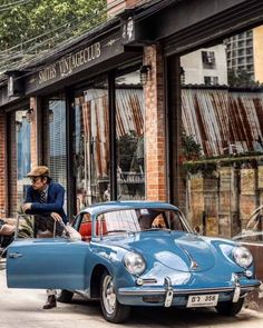 an old blue car parked in front of a building