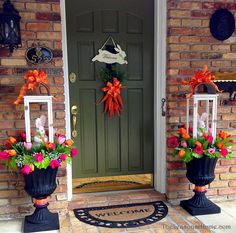 two large black planters filled with flowers sitting in front of a green door