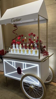 a cart that has some drinks on it with flowers in the back and lights behind it