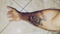 a man's arm with a rose tattoo on it and his hand extended out to the side