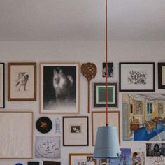 a room filled with lots of framed pictures on the wall next to a light fixture