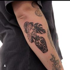 a man with a tattoo on his arm holding a vase filled with flowers and plants