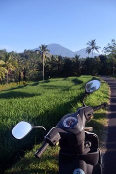 the motorcycle is parked on the side of the road in front of some palm trees