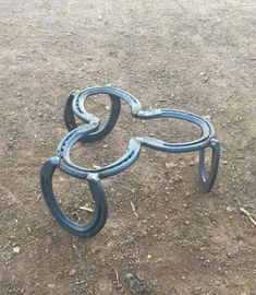 two metal horseshoes laying on the ground in the middle of dirt and gravel area