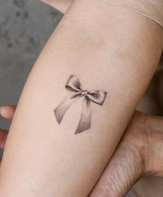 a woman's arm with a tattoo that has a bow on it