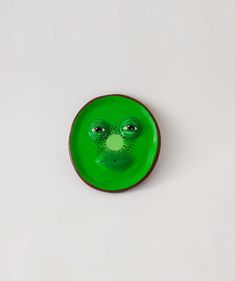 a green plate with a face painted on the side and eyes drawn to look like an alien