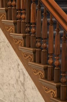 an ornate wooden stair case with marble flooring