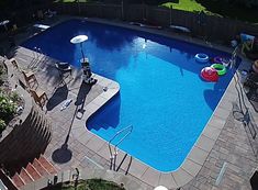 an aerial view of a swimming pool with inflatable toys on the ground and chairs around it