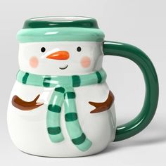 a green and white mug with a snowman on it