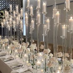 a long table with candles and flowers in vases on top of it, along with place settings