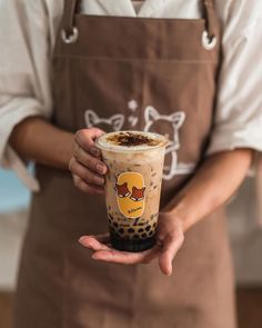 a person in an apron holding a cup of coffee