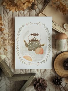 a card with an image of a teapot on it next to some pine cones