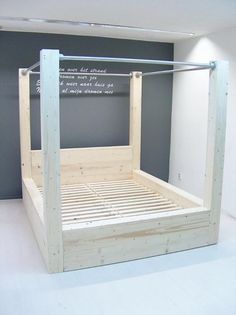 a wooden bed frame sitting on top of a white floor next to a chalkboard wall