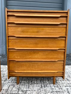 a wooden dresser sitting on top of a carpeted floor next to a metal door