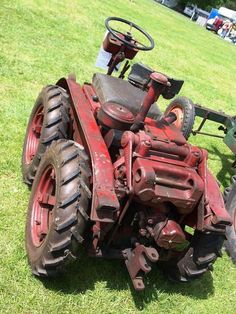 an old red tractor sitting in the grass