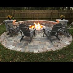 an outdoor fire pit with chairs around it