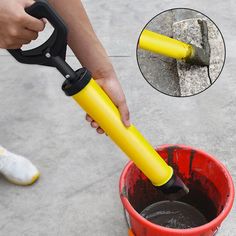 a person is using a yellow handle to pour water into a red bucket and onto the ground