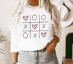 a woman wearing a white shirt with hearts and crosses on the front that says xoxo