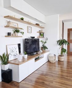 a living room filled with furniture and a flat screen tv on top of a wooden shelf