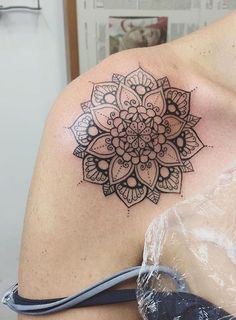 a woman's shoulder with a tattoo on the back of her arm and an intricate flower design