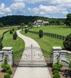 a driveway leading to a large house with a gate in the middle and landscaping around it