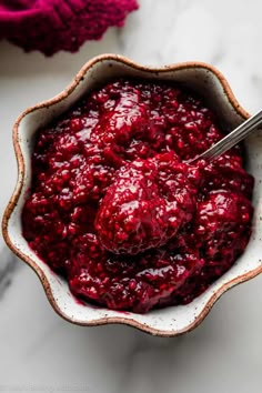 a bowl filled with cranberry sauce on top of a white countertop next to a red towel