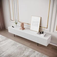 a white table with two drawers and a vase on it next to a framed photograph