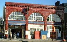 an old brick building with many windows and people standing outside it on the street corner