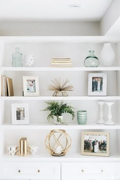 a white book shelf with pictures, vases and other items on top of it