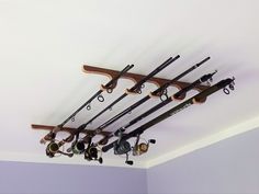 there are many fishing rods and reels hanging from the ceiling