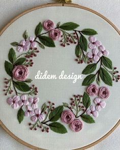 a hand embroidered wreath with pink flowers and green leaves