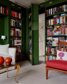 a living room filled with lots of green bookshelves next to a white couch