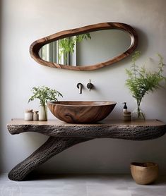 a bathroom sink sitting under a mirror next to a wooden table with plants on it