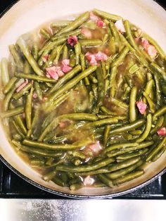 green beans and ham cooking in a pan on the stove top, with water running down the side