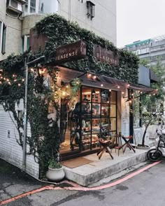 a store front with plants growing on the side of it's windows and doors