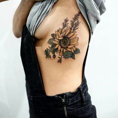 a woman with a sunflower tattoo on her upper arm and chest, wearing overalls